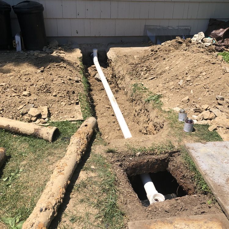 A white pipe is being installed in a hole in the ground