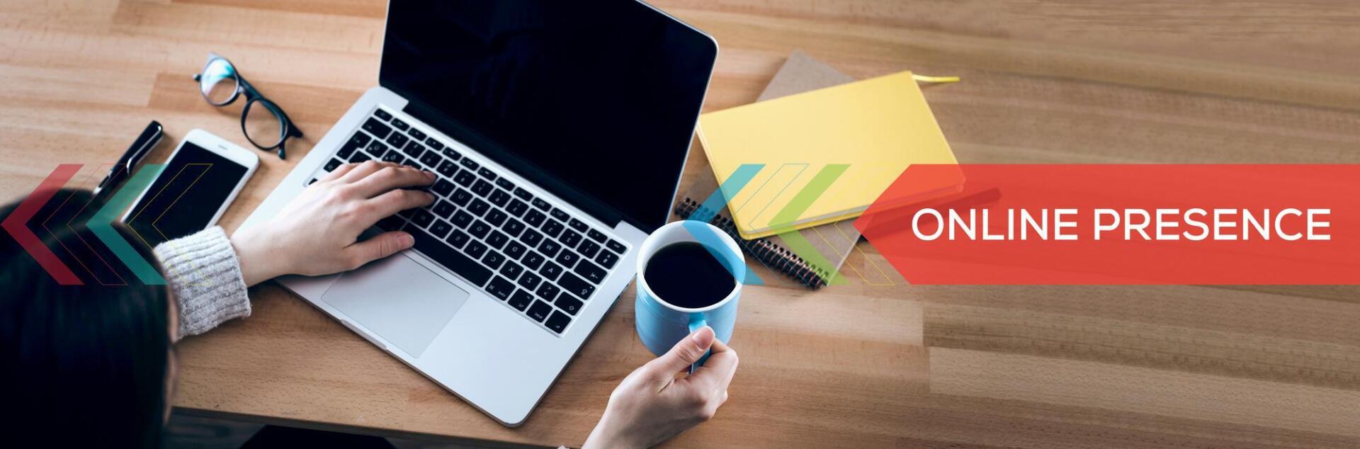A person is typing on a laptop computer while holding a cup of coffee.
