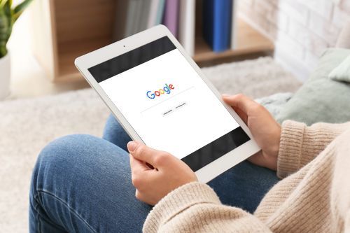 a woman is sitting on a couch using a tablet computer .