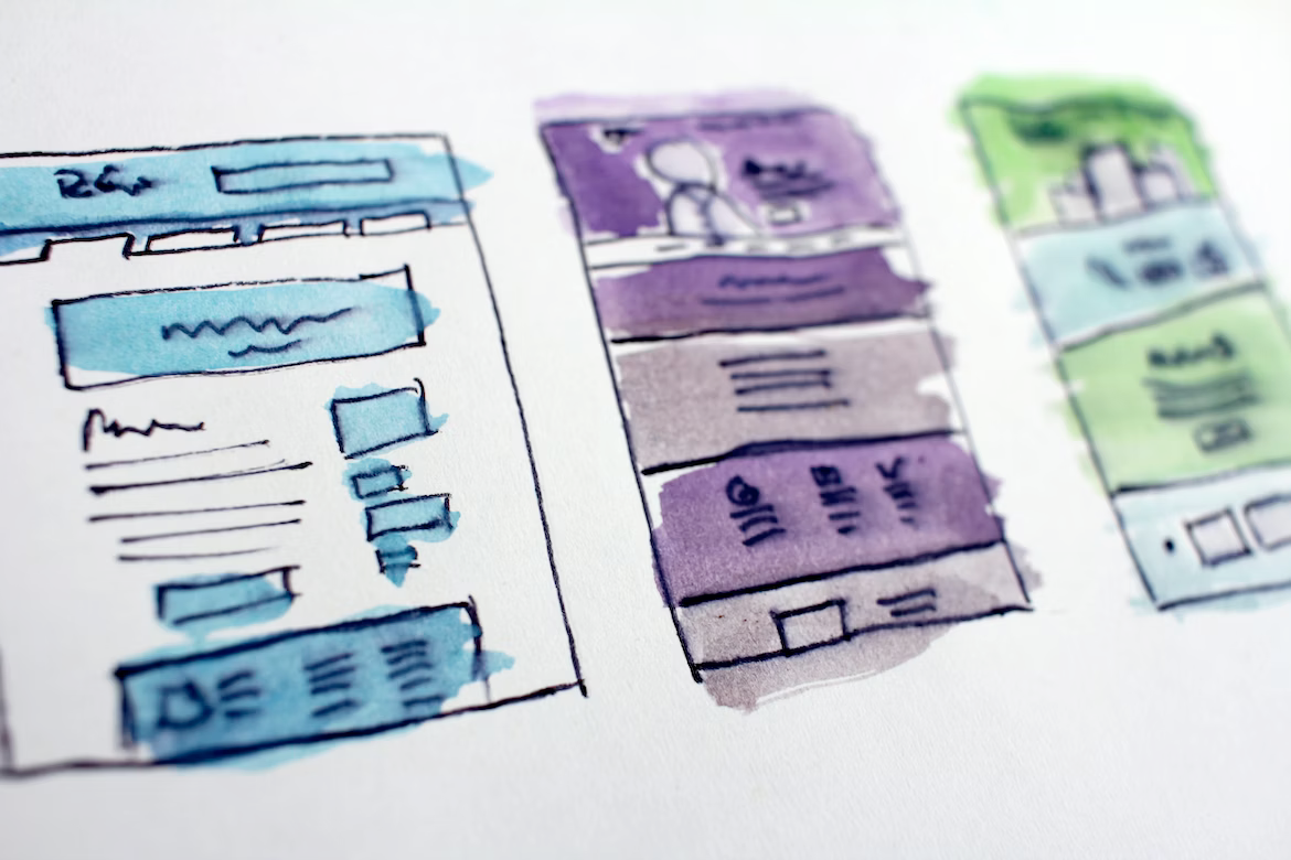 Three watercolor drawings of a website on a white surface