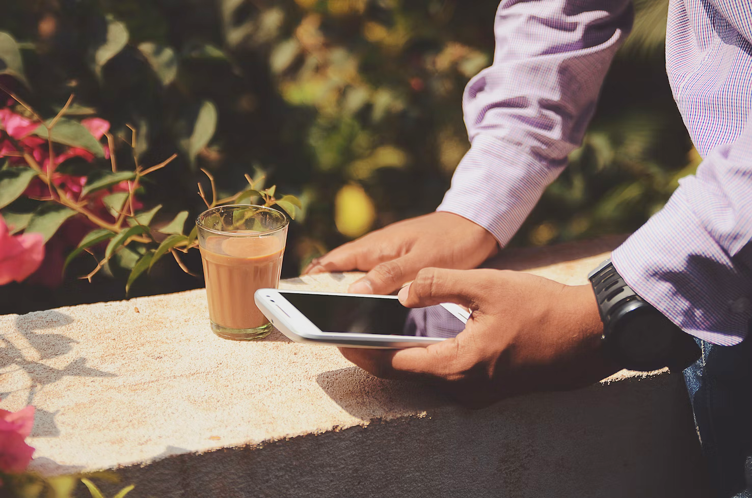 a man is holding a cell phone next to a glass of tea .