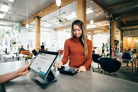 a woman is using a tablet to pay for something in a store .