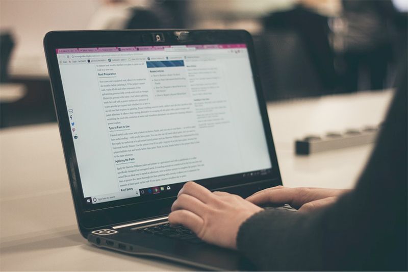 Person typing on a laptop with a website open in a modern office.