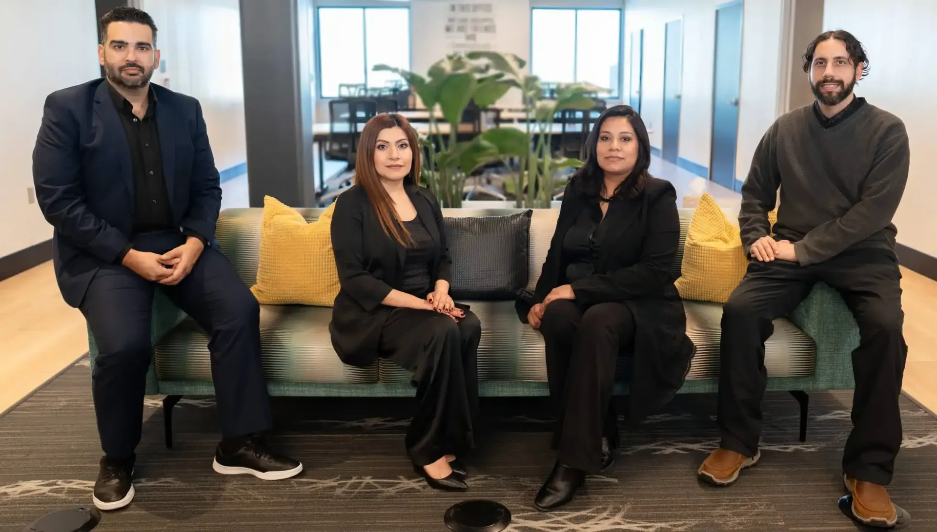 Four coworkers sitting on a green couch in a modern office lounge