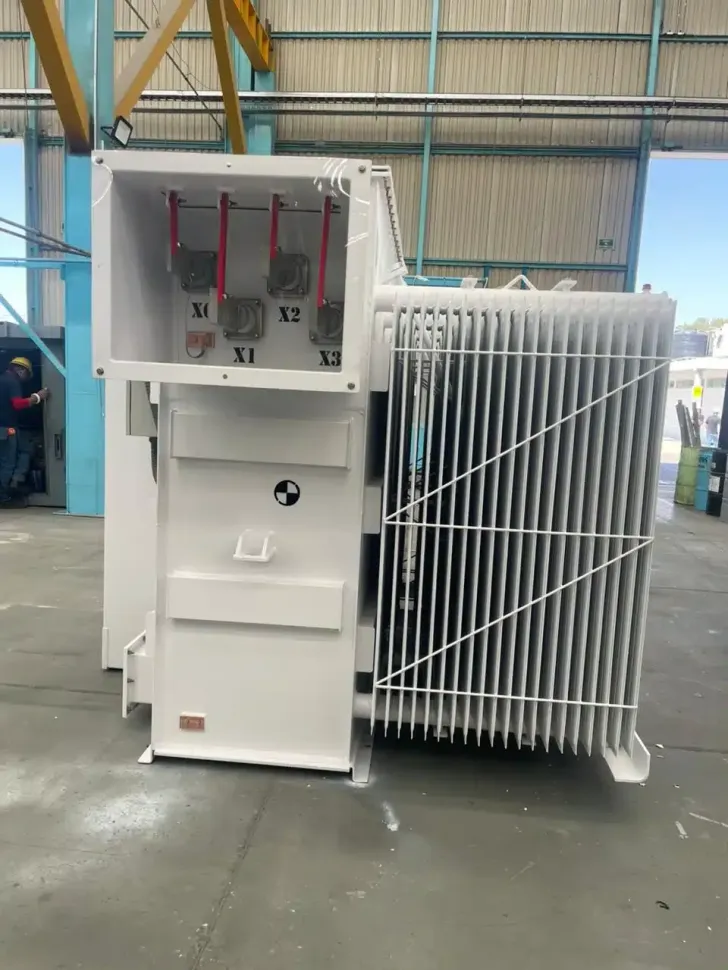 Large white industrial machine with open panel and side cooling fins in a factory warehouse