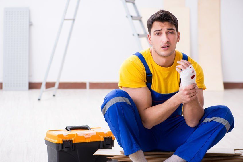 A man is sitting on the floor with a bandaged hand.
