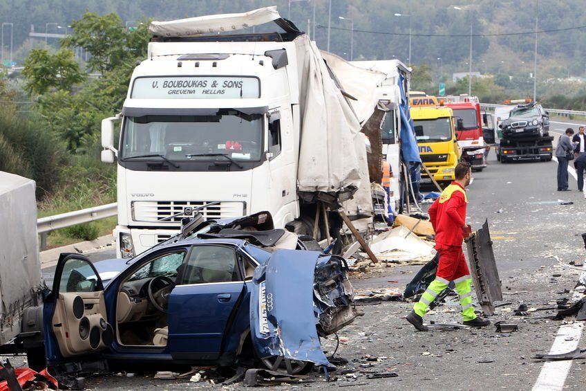 A man in a red shirt is walking in front of a volvo truck