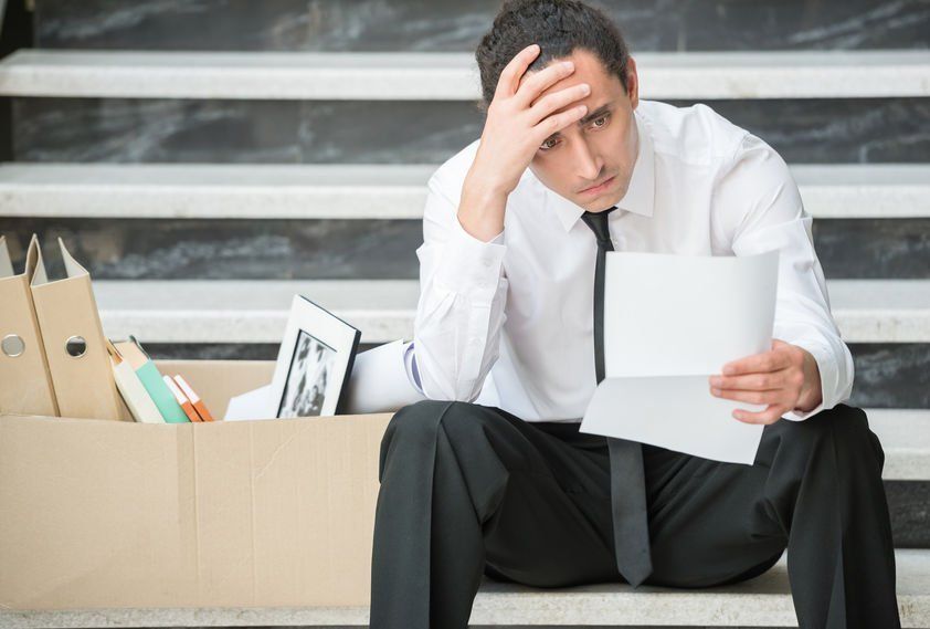 A man is sitting on the stairs with a box of his belongings.