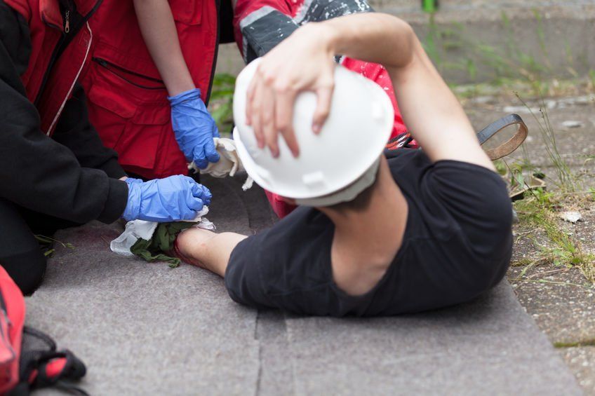 A man is laying on the ground with a helmet on his head.