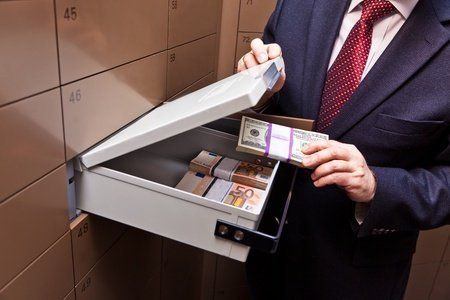 A man in a suit and tie is taking money out of a safe.