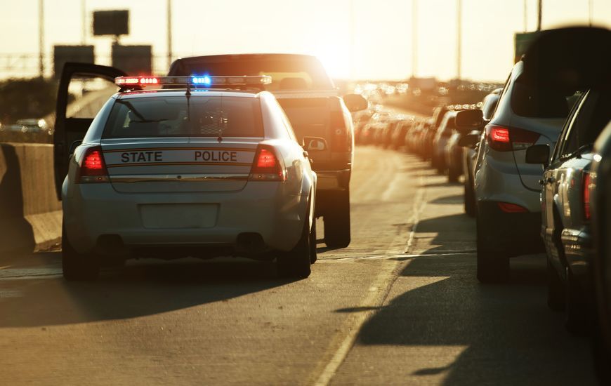 A police car is driving down a highway next to a tow truck.