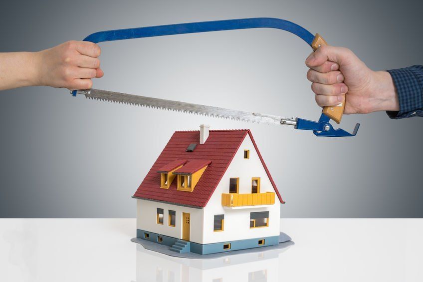 A person is cutting a model house with a saw.