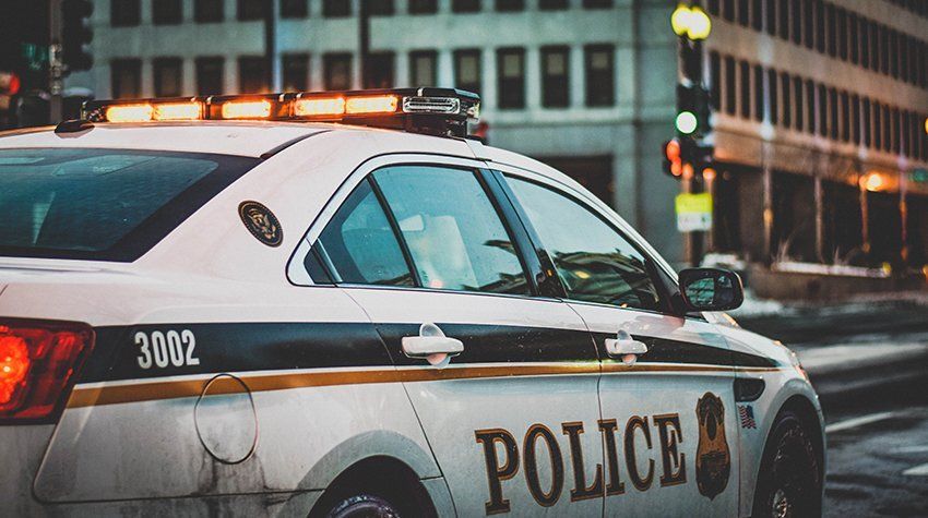 A police car is parked on the side of the road in front of a building.