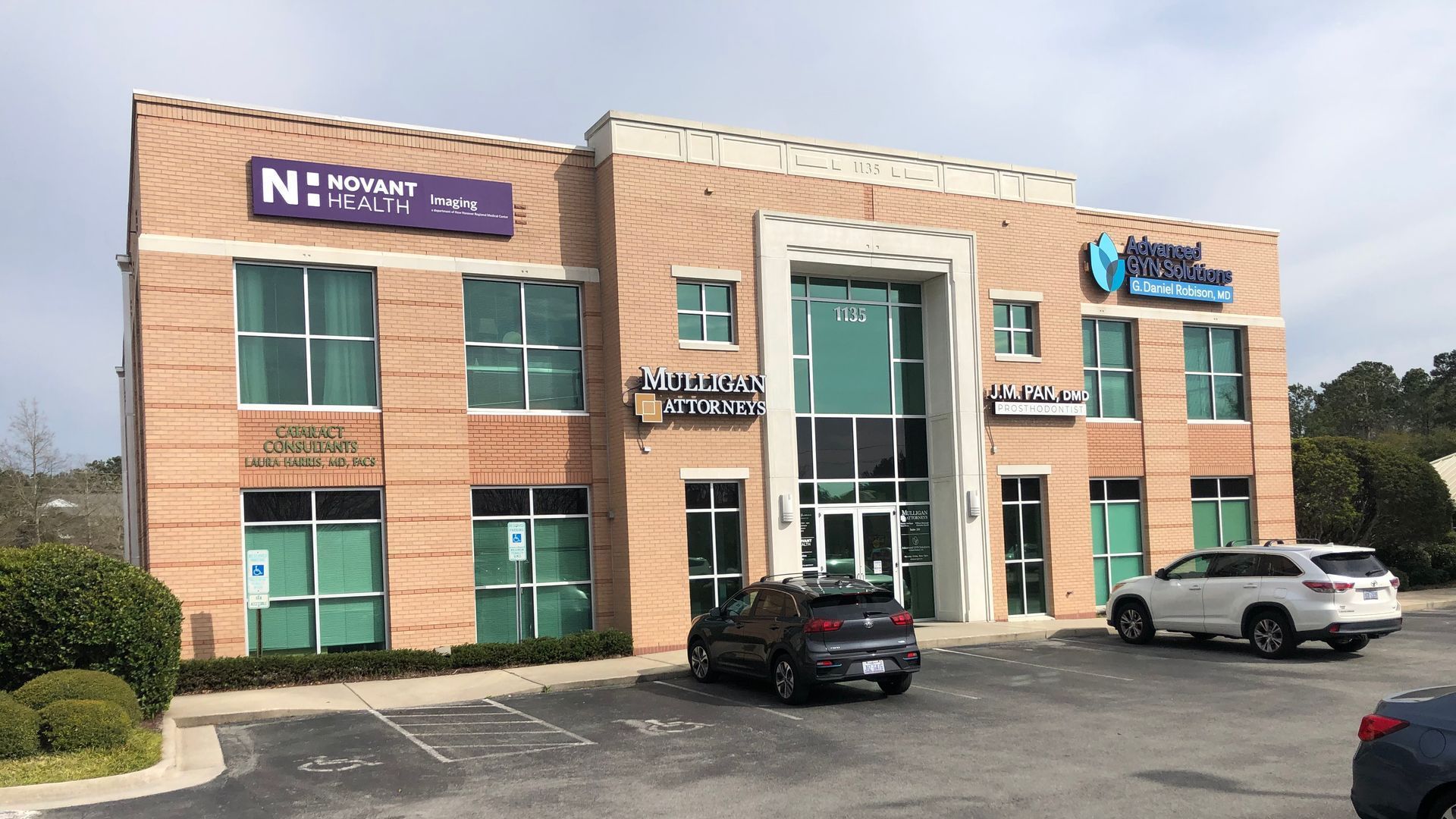 A large brick building with a lot of windows and cars parked in front of it.