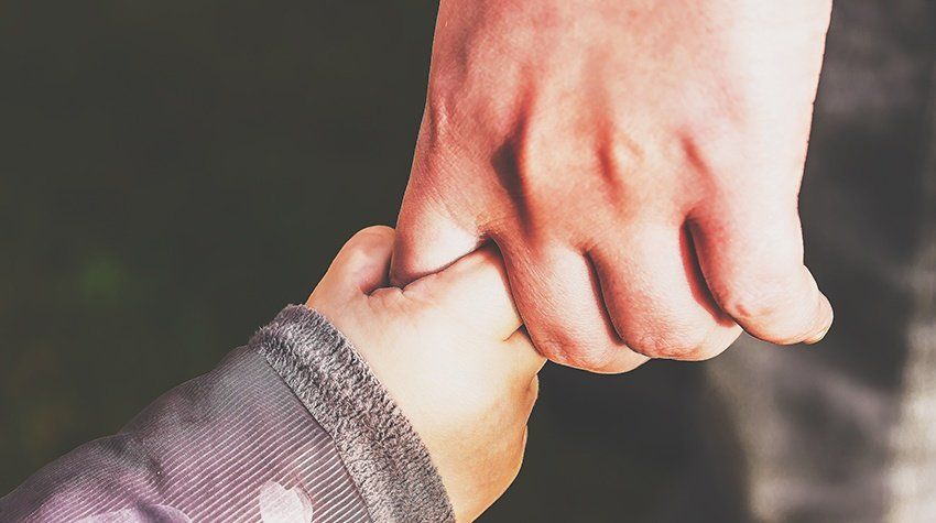 A close up of a person holding a child 's hand.
