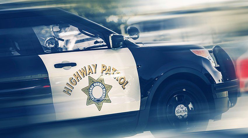 A black and white highway police car is driving down the road