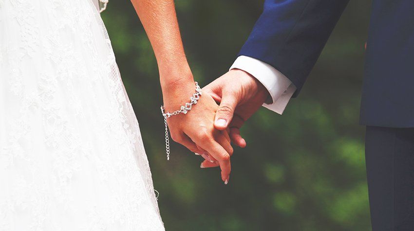 A bride and groom are holding hands on their wedding day.