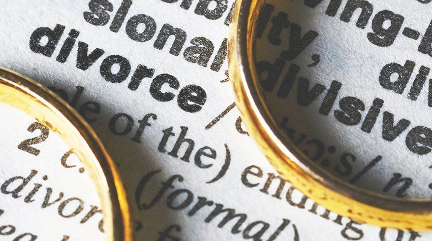 Two wedding rings are laying on top of a dictionary page that says divorce