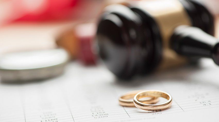 A pair of wedding rings sitting on top of a calendar next to a judge 's gavel.