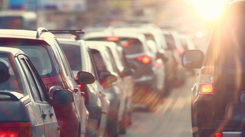 A row of cars are sitting in traffic on a city street.
