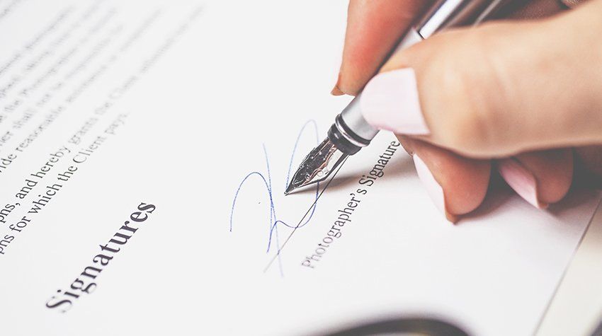A woman is signing a document with a fountain pen.