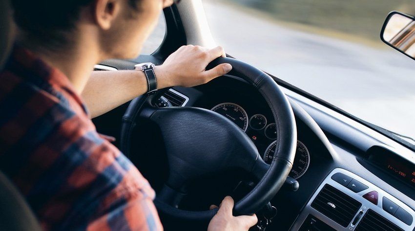 A man is driving a car on a road.