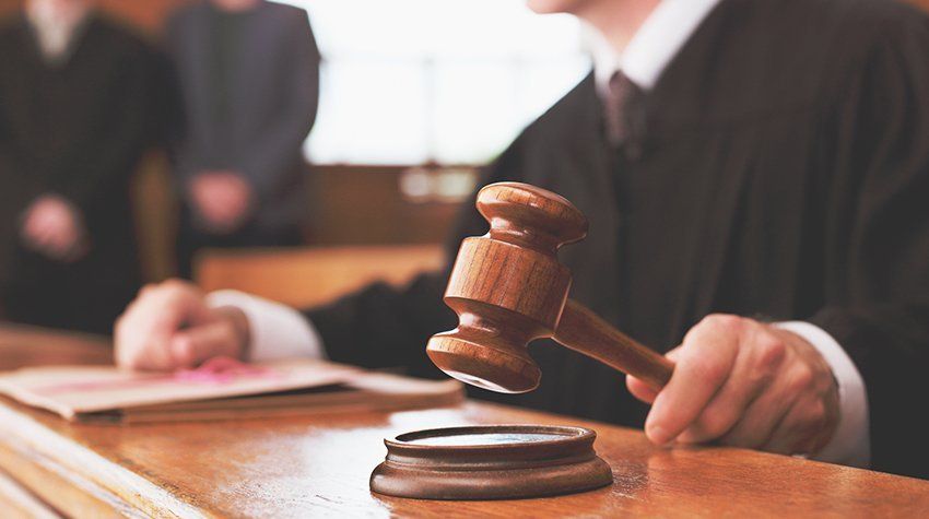 A judge is holding a wooden gavel in a courtroom.