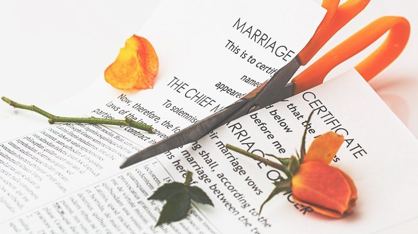 A pair of scissors laying on top of a marriage certificate
