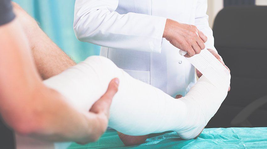 A doctor is putting a cast on a patient 's leg.