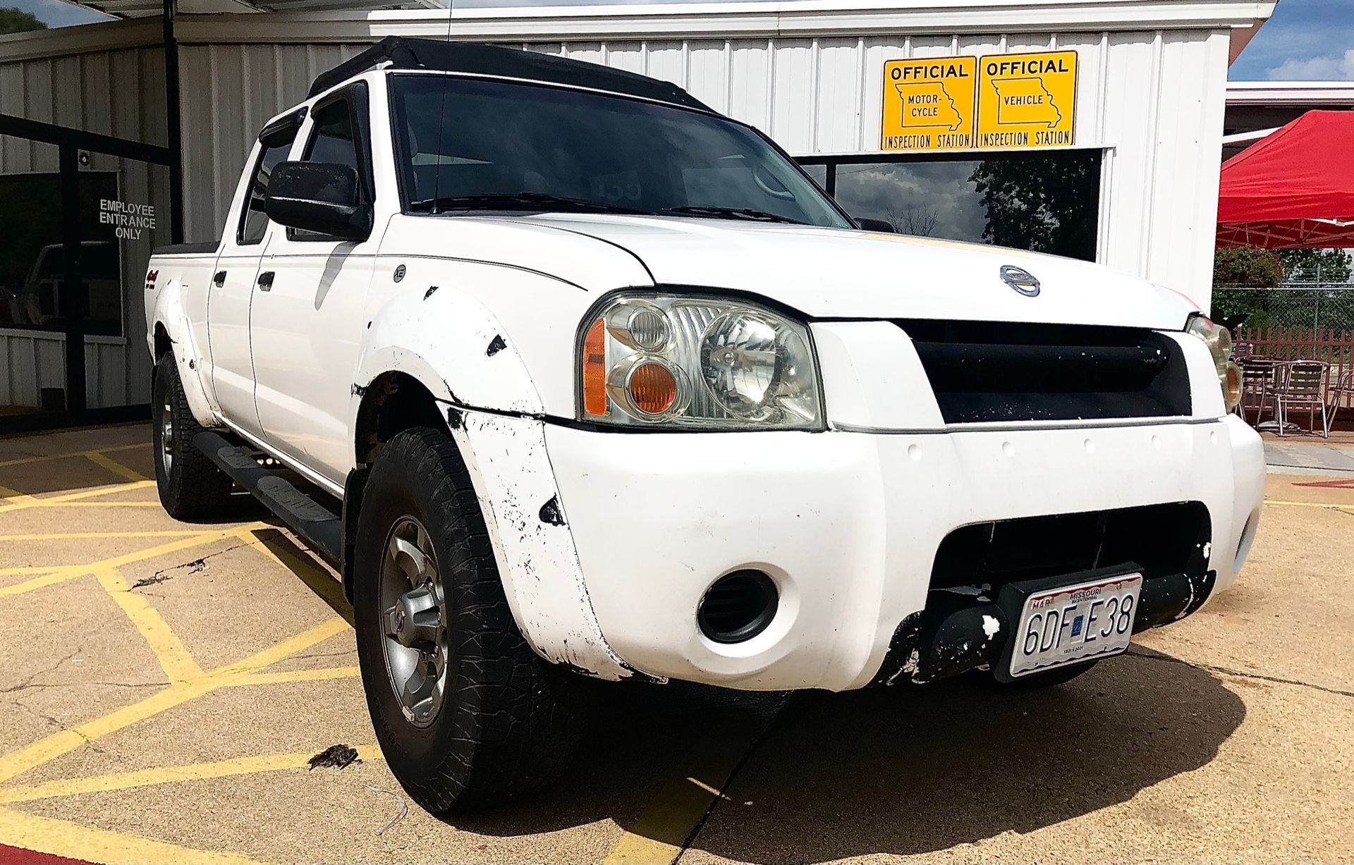 White SUV parked in a lot with front-end damage and a visible dent on the bumper | Dependable Automotive