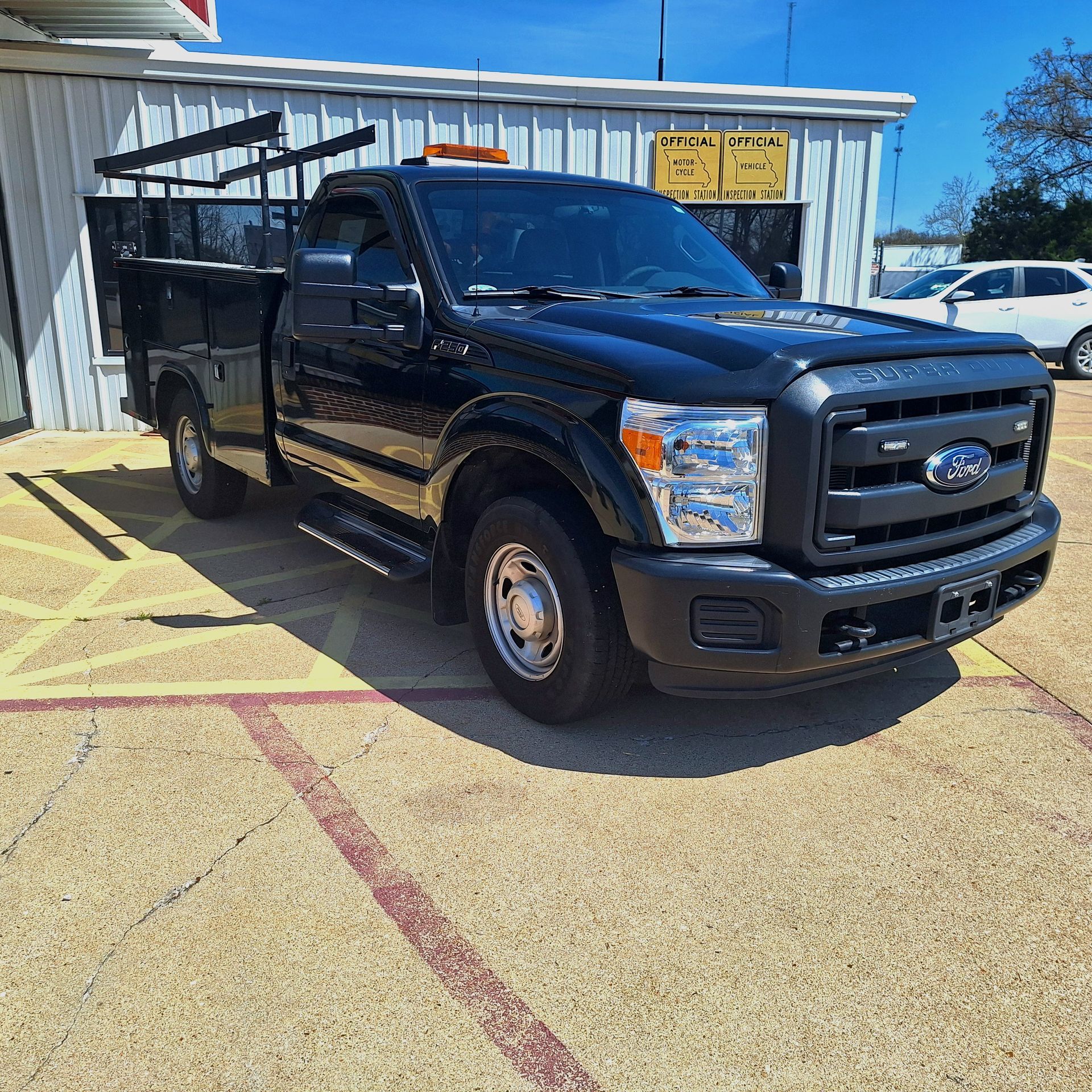 Black Ford pickup truck with a covered cargo bed parked outside a metal building. | Dependable Automotive