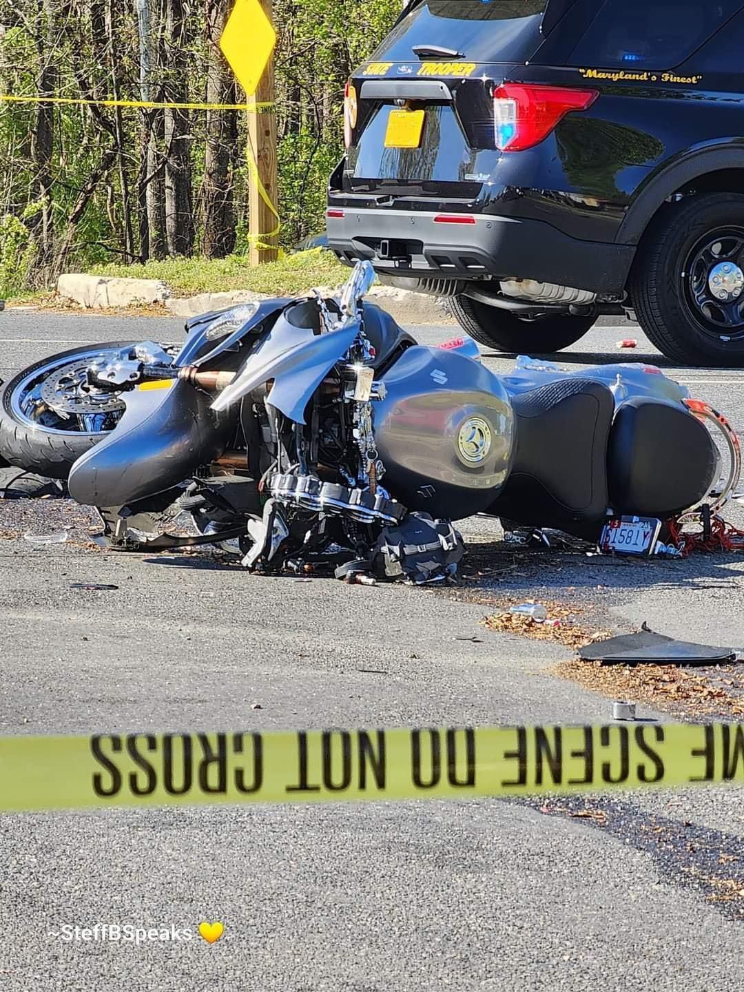 A motorcycle is laying on the side of the road next to a police car.