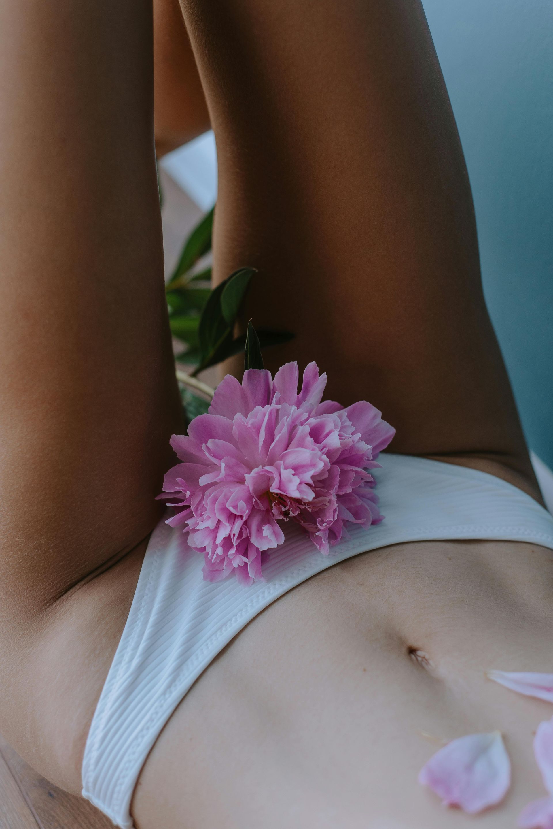 Person in white underwear with pink flowers on torso, reclining with legs raised.