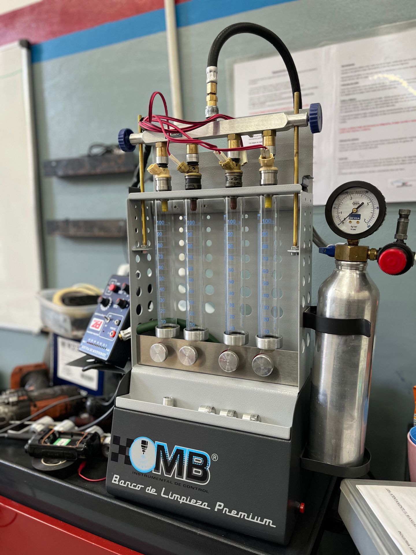 Máquina de limpieza y prueba de inyectores de combustible en un garaje con un manómetro incorporado.