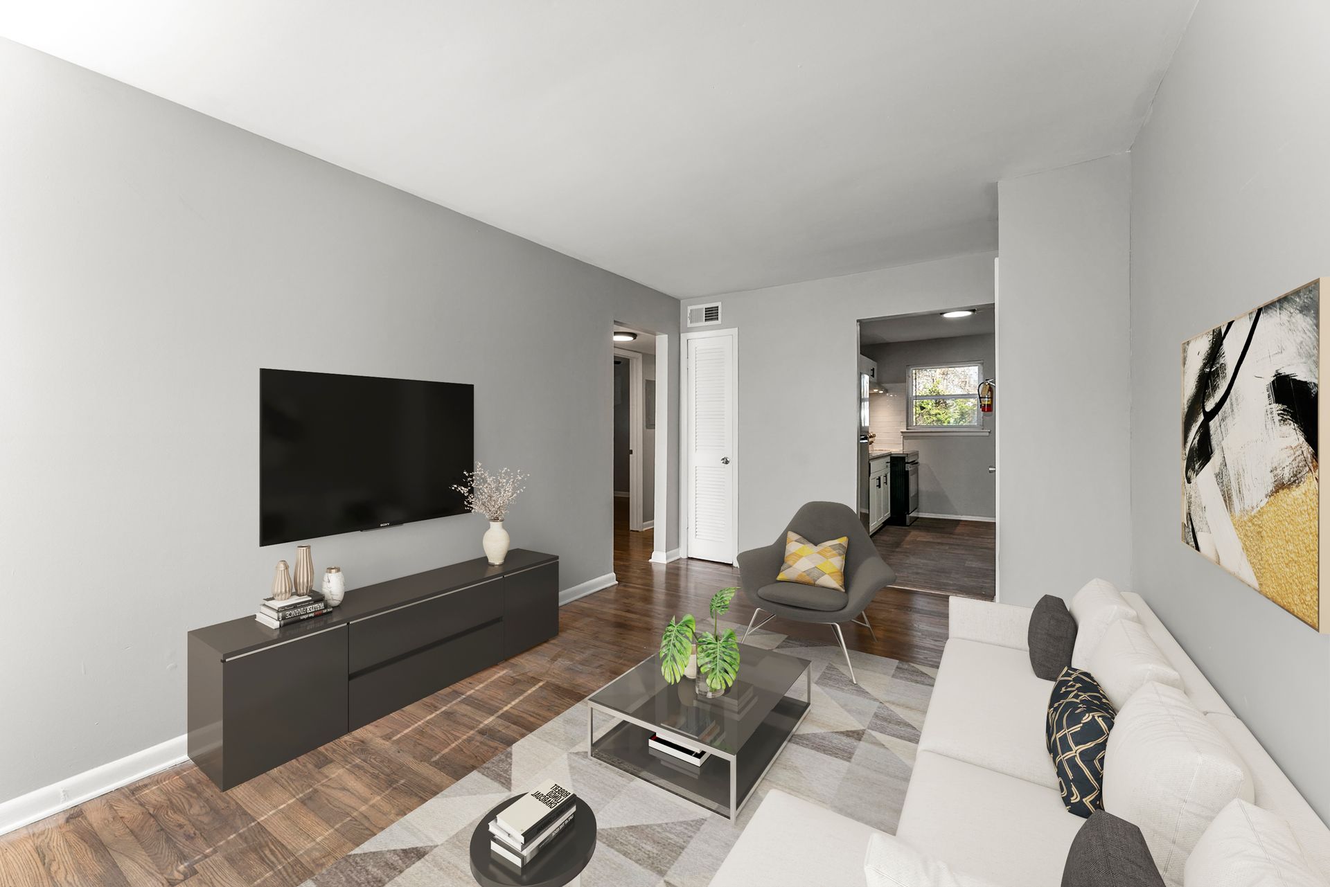 Modern living room with gray walls, wall-mounted TV, sectional sofa, coffee table, and patterned rug