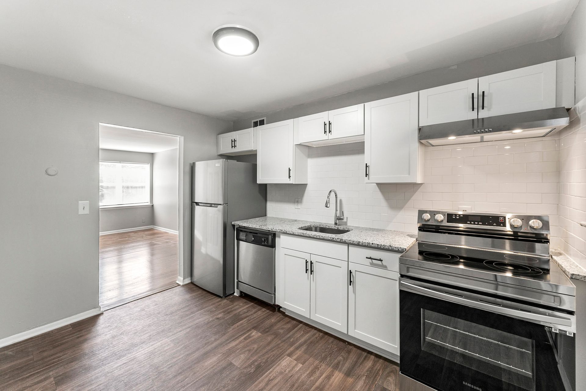 Bright white kitchen with stainless steel appliances, gray cabinets, and wood flooring