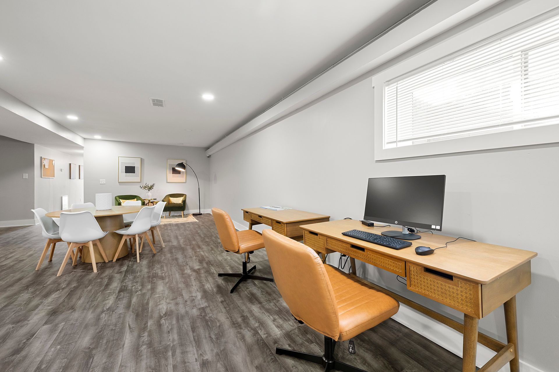 Modern office lounge with desks, orange chairs, computers, and a white meeting area