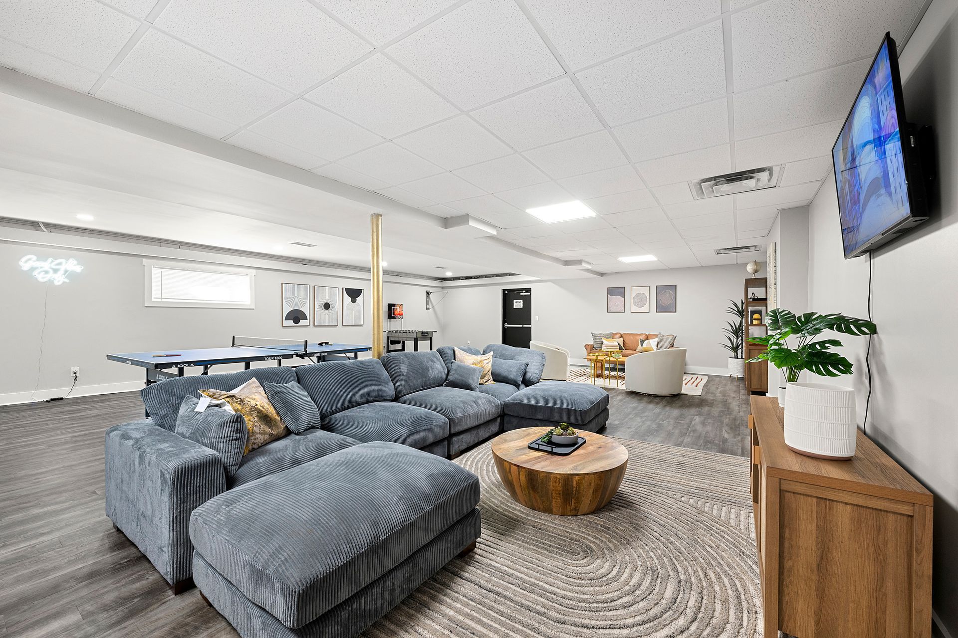 Modern lounge with blue sectional sofa, round coffee table, wall TV, and patterned carpet