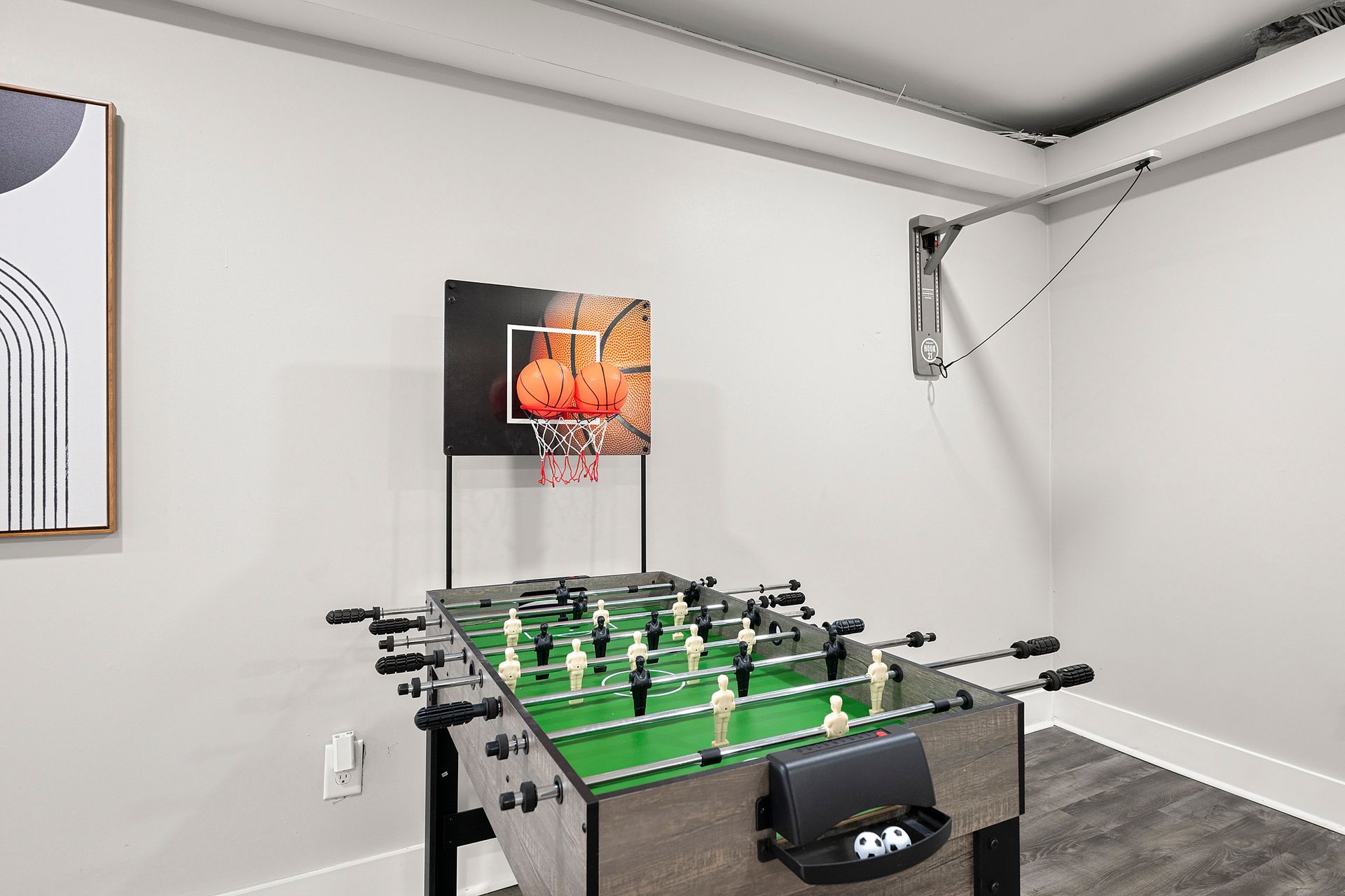 Foosball table in a finished basement game room with white walls and gray carpet