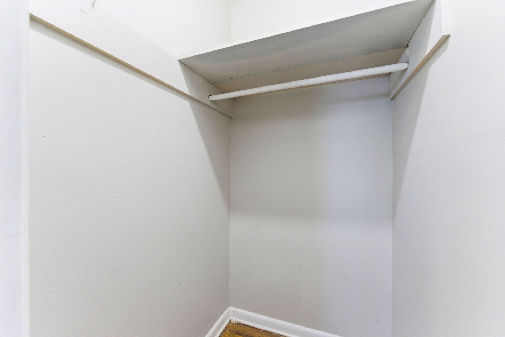 Empty white walk-in closet with shelves and hanging rod