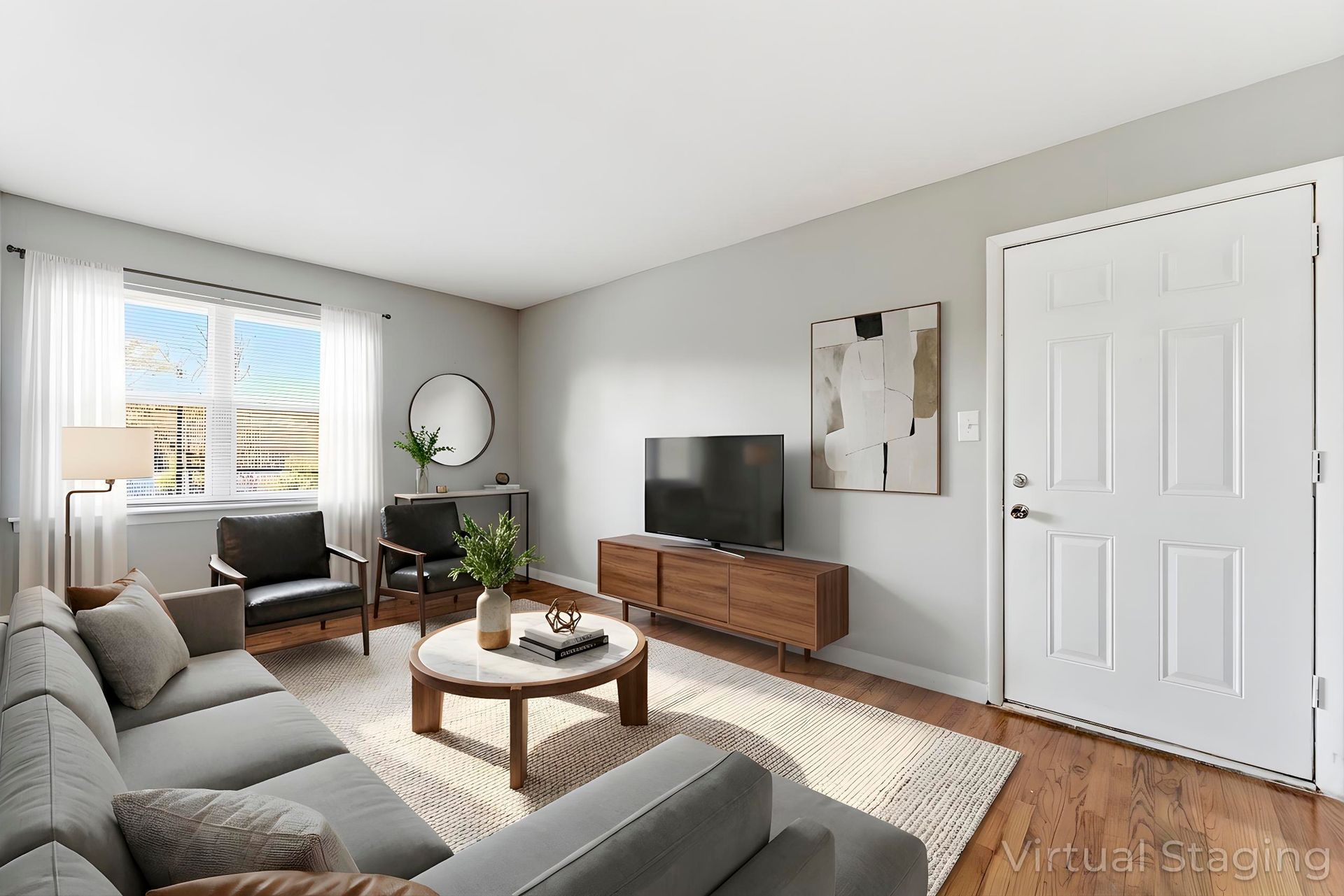 Bright living room with gray sofa, wooden TV console, large window, and white double doors