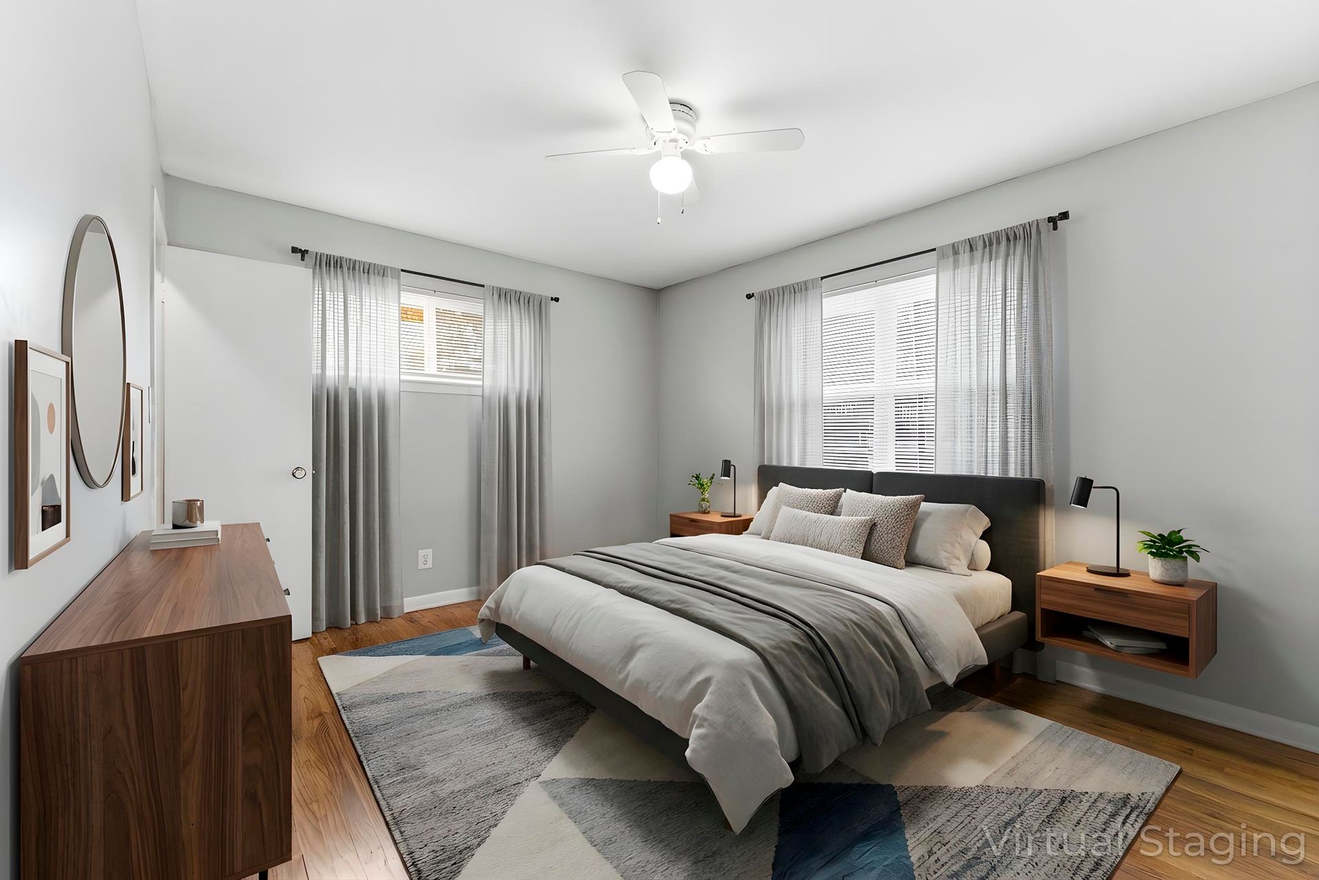 Bright modern bedroom with a bed, gray bedding, nightstands, rug, and windows with sheer curtains