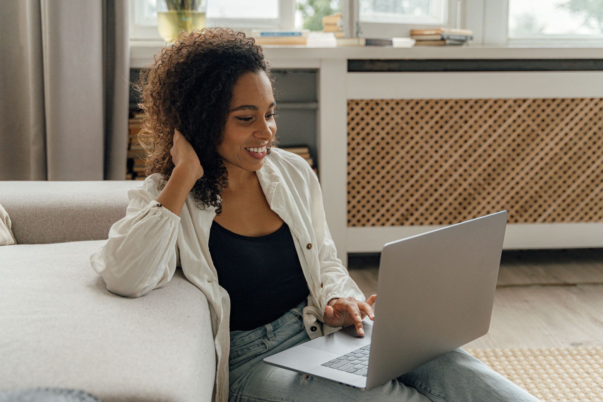 Woman on a sofa using a laptop in a bright living room