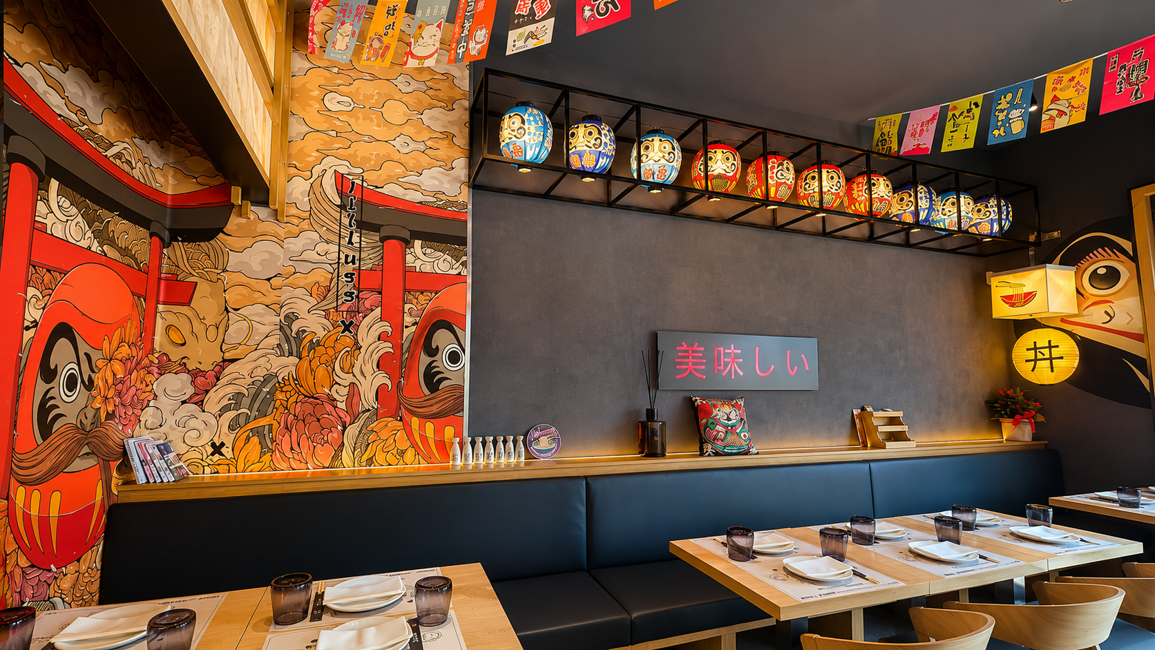 Interni di un ristorante in stile giapponese dai colori vivaci, con pareti decorate con murales, lanterne e tavoli apparecchiati con cura.