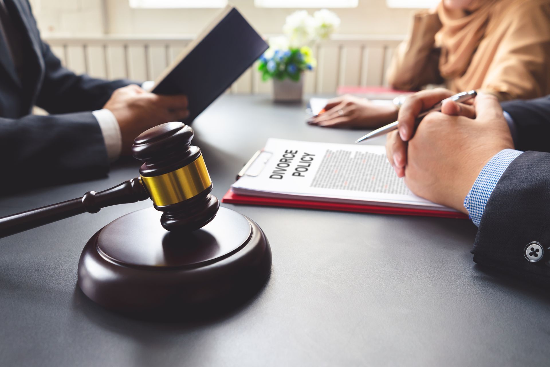 A couple consulting a lawyer about a divorce agreement. Lawyer meeting with gavel and document labeled “court case” on conference table