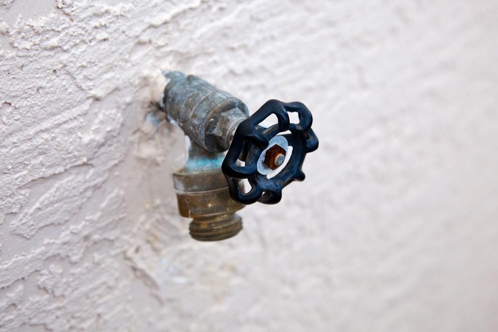 A Close Up of a Faucet With a Blue Handle on a White Wall — Nightcliff Plumbing & Gas In Coconut Grove, NT