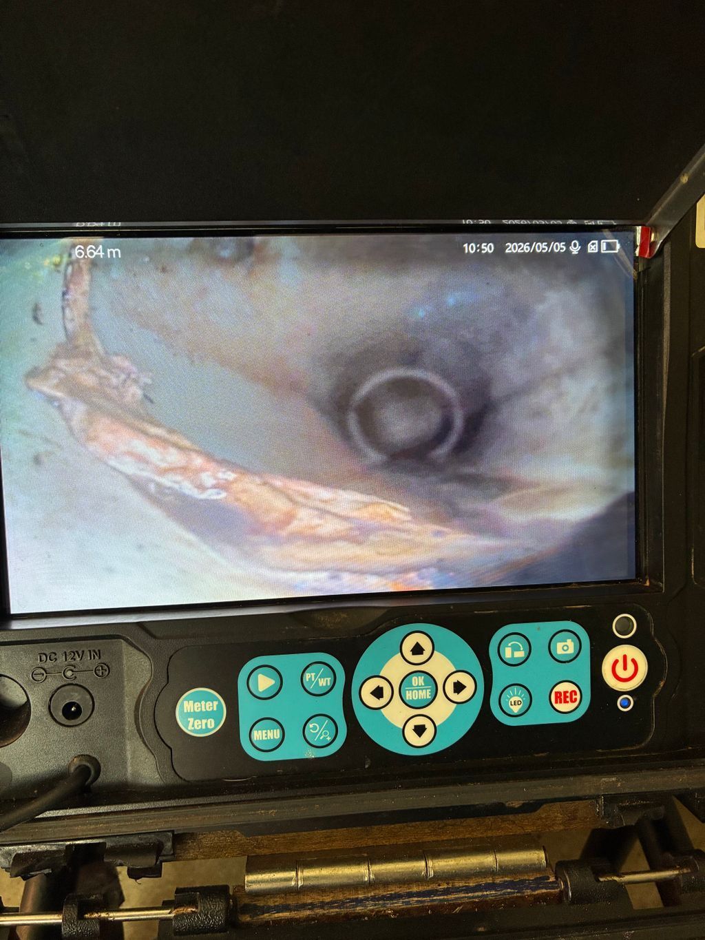 A handheld monitor shows a blurry medical endoscope view of an inner tube with control buttons below — Nightcliff Plumbing & Gas In Coconut Grove, NT
