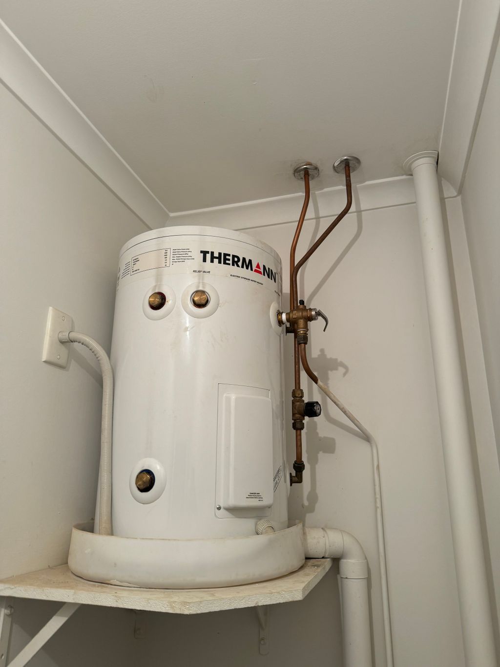 White Thermann water heater with exposed copper pipes on a shelf in a small closet — Nightcliff Plumbing & Gas In Humpty Doo, NT