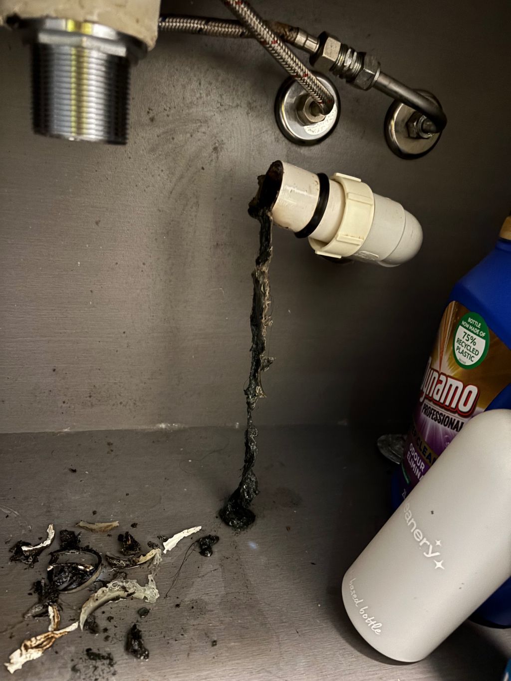 Under-sink cabinet with a leaking pipe, black water trail, and cleaning supplies on the shelf — Nightcliff Plumbing & Gas In Coconut Grove, NT