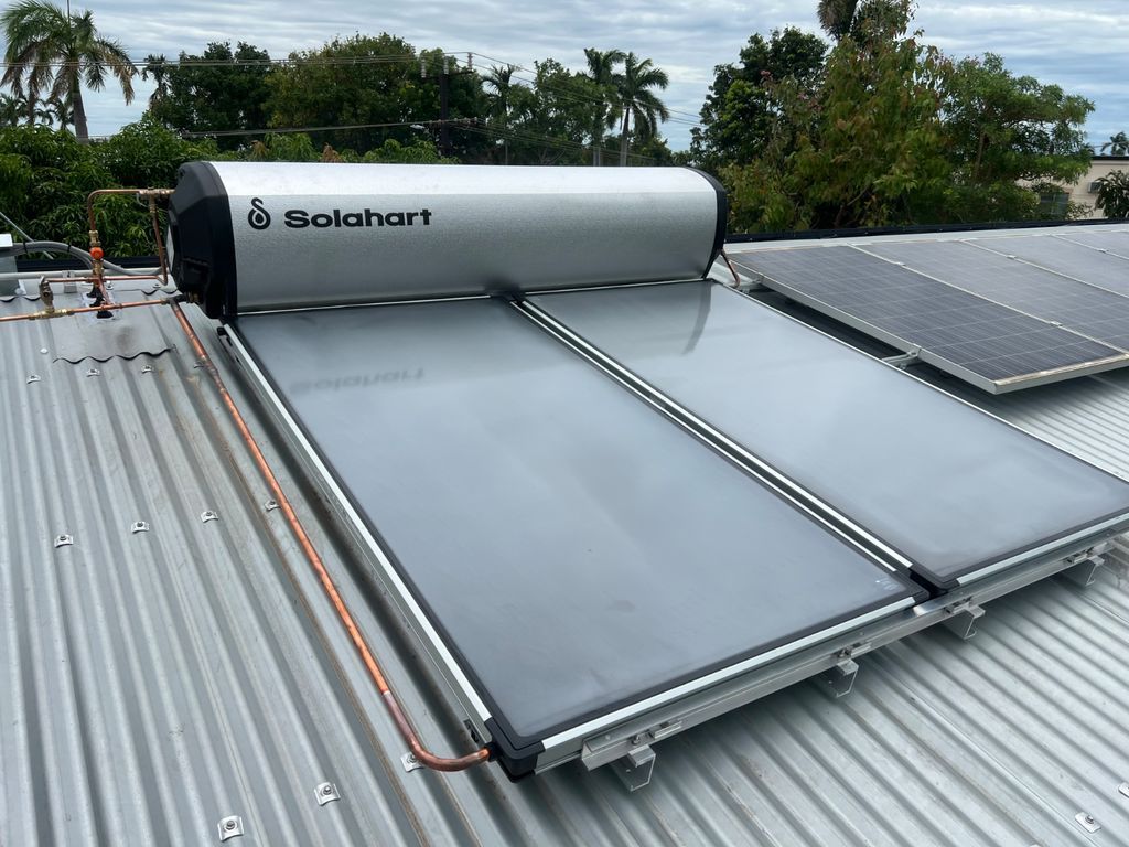 Solar water heater panels on a corrugated metal roof under a cloudy sky. — Nightcliff Plumbing & Gas In Coconut Grove, NT